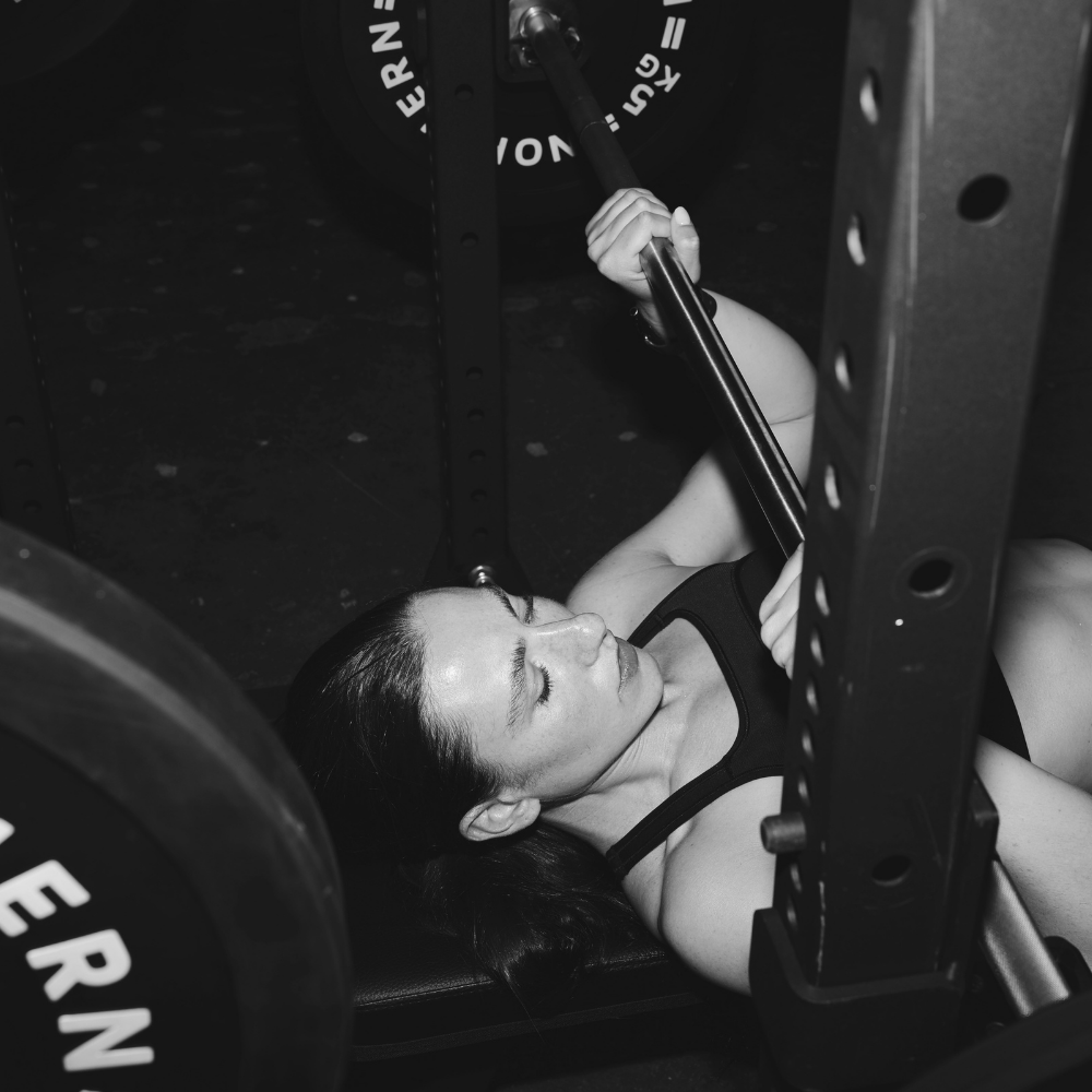 Performing bench press in a half rack using bumper plates in barbell